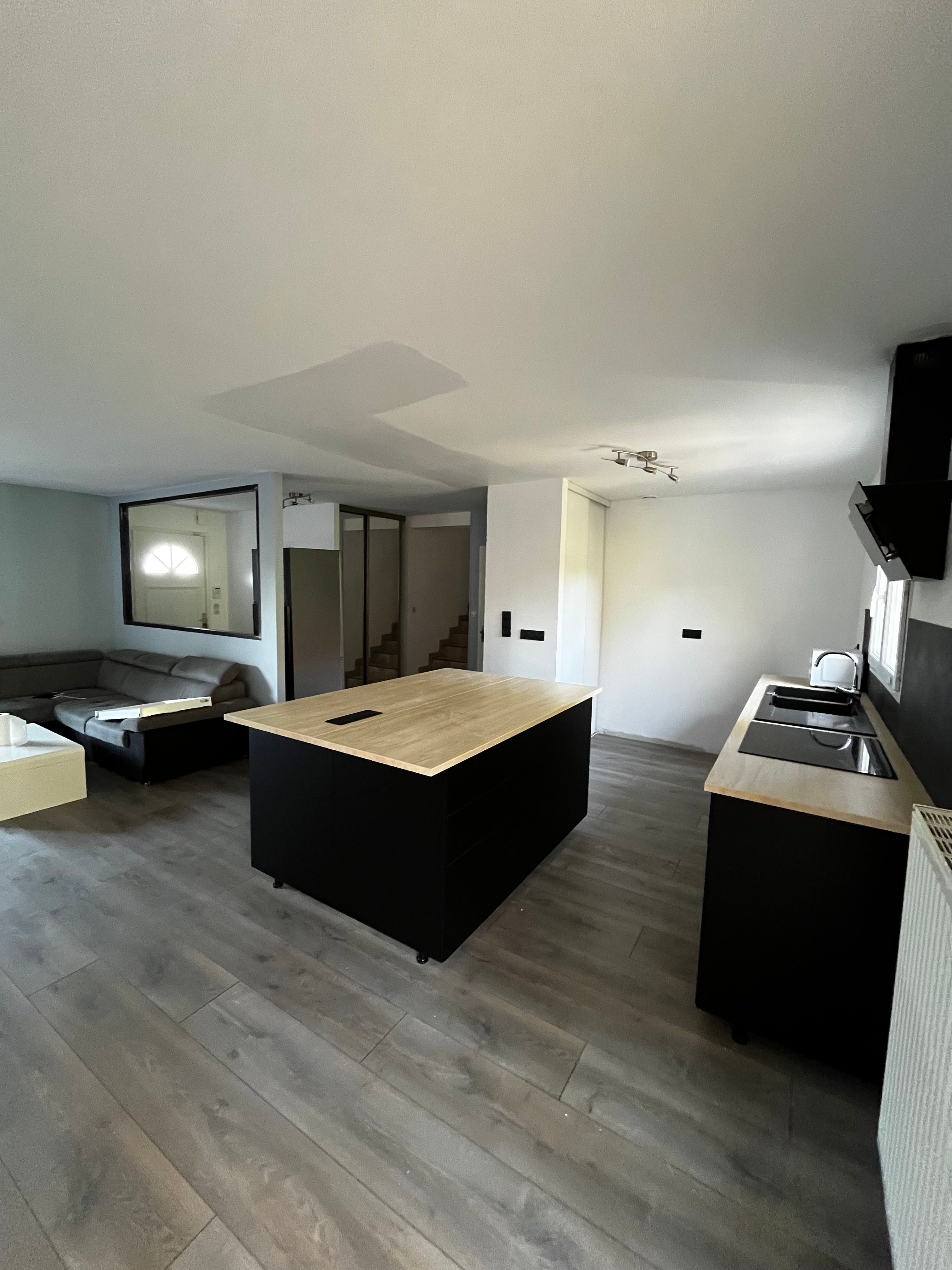 Cuisine noire moderne avec îlot central et plan de travail bois